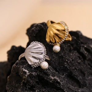 Macro detail of gold scallop ring with pearl and crystals on black volcanic rock
