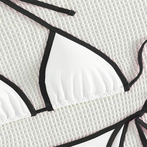 Close-up of a white triangle bikini top with black contrast trim and ruched detailing