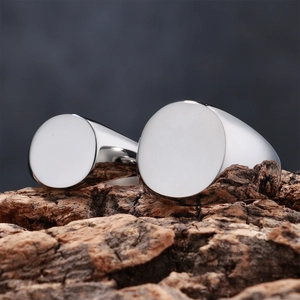 Two polished silver stainless steel signet rings placed on a natural tree bark background