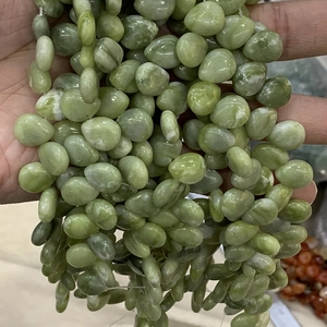 Close-up of green watermelon crystal teardrop beads held by hand for jewelry making