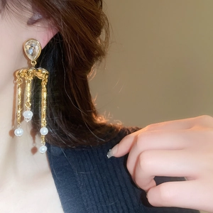 Détail de longues boucles d'oreilles dorées avec cristal goutte et perles sur mannequin