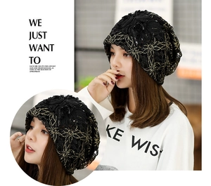 Detail of a black lace beanie cap with floral patterns and golden sequin embroidery