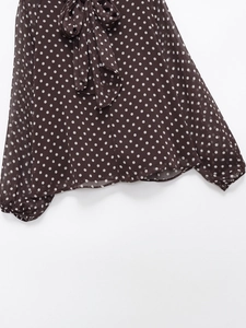 Detailed view of women's polka dot blouse with bow-knot neckline and long sleeves