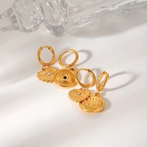 Close-up of golden heart and circular evil eye earrings with zircon inlays