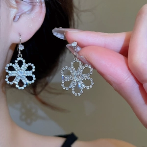 Detail of silver flower earrings with sparkling crystals shown on a model's ear