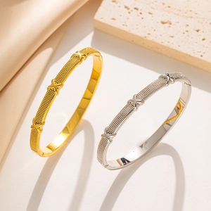 Detailed macro view of gold and silver stainless steel bangles with textured grid pattern