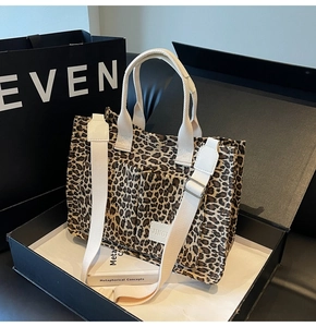 Detail of leopard print canvas tote bag featuring double handles and adjustable white strap