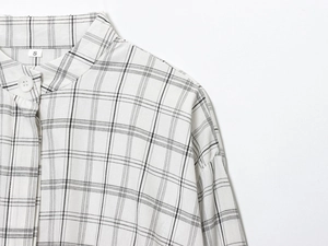 Gros plan du col et des boutons d'une veste chemise à carreaux noirs et blancs