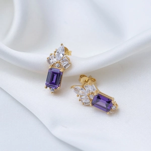 Detailed macro view of luxury rectangle purple zircon stud earrings on white silk