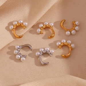 Détail de boucles d'oreilles perles dorées et argentées sur un tissu en soie beige