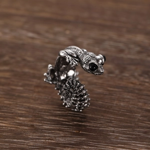 Detailed macro view of a vintage gothic frog ring with black eyes on a dark wood table
