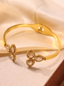 Macro detail of gold flower bangle with 5A cubic zirconia stones on silk background
