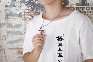 Detailed view of a silver and black cross necklace worn by a model in a street style setting