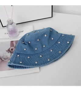 Close-up of washed blue denim bucket hat with sparkling silver rhinestones on a white desk