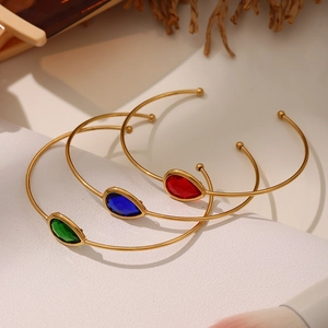 Three gold-plated open bangles featuring pear-cut green blue and red stones