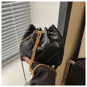 Detail of black quilted bucket bag featuring gold chain and elegant pearl tassel drawstring