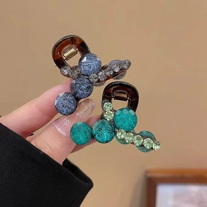 Detail of small hair clips with emerald beads and sparkling rhinestones for women