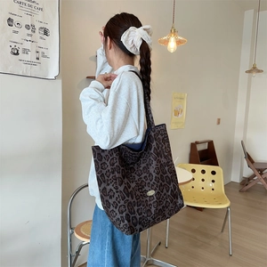 Close-up of leopard print tote bag with metal nameplate in a stylish cafe setting