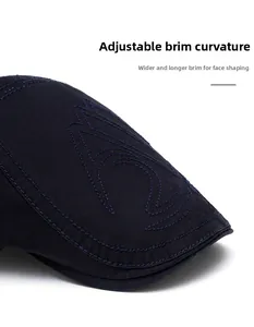 Detail of navy cotton newsboy cap featuring wide foldable brim and abstract embroidery