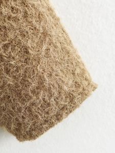 Detail shot of the coarse brown natural fiber texture on the V-neck autumn jacket