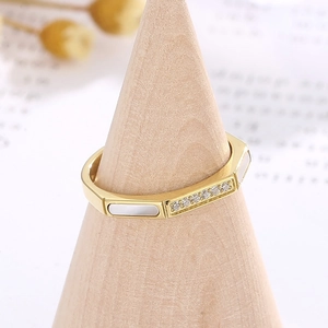 Macro detail of gold octagonal ring with white shell inlay and zircon pavé on a stand