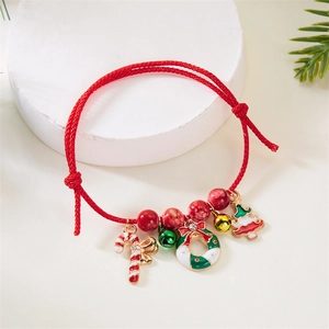 Detail of red braided Christmas bracelet with a wreath, candy cane and tree pendants