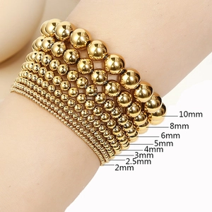 Detail view of golden beaded bracelets showing bead sizes from 2mm to 10mm diameter