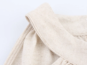 Detailaufnahme der beigen Leinenstruktur und Nähte am sommerlichen Midikleid
