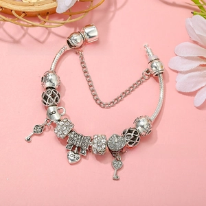 Detail of silver charm bracelet featuring love heart and key pendants on snake chain