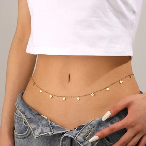 Close-up of a stylish gold waist chain with clover pendants worn on a woman's waist