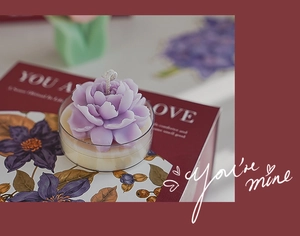 Macro view of purple flower scented candle with glass base on premium red gift box