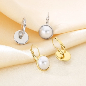 Detail view of round shell pearl earrings in gold and silver finish on silk