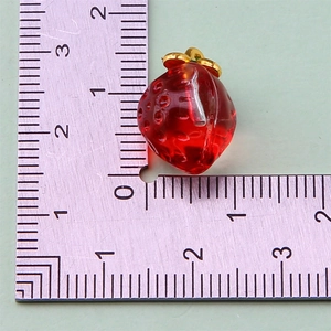 Mini resin strawberry charm with gold hook measured on a ruler for DIY jewelry