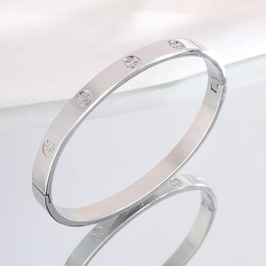 Macro shot of silver stainless steel bangle with engraved circular patterns on white satin