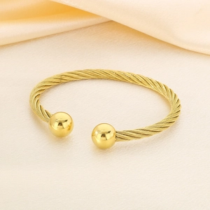 Detail of 18K gold plated cable wire twisted bangle with polished metal bead ends