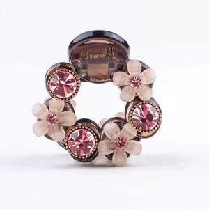 Elegant camellia hair claw with pink rhinestones and resin flowers on a brown clip