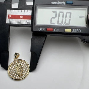 Macro shot showing 20mm diameter measurement of gold Virgin Mary pendant with cubic zirconia