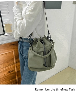 Side view of an army green nylon drawstring bucket bag with adjustable shoulder strap