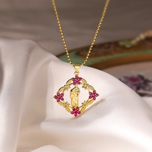 Macro shot of 18K gold plated rhombus pendant with religious relief and red zircon