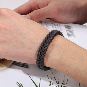 Detail of dark brown braided leather bracelet for men with metal texture clasp on wrist