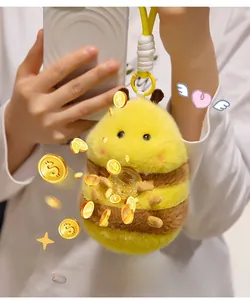 Close-up of plush bee keychain holding a gold coin with a yellow clip and braided rope