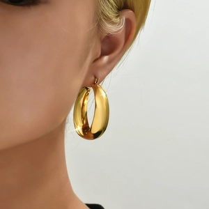 Polished chunky gold hoop earrings in stainless steel worn by a model in profile view