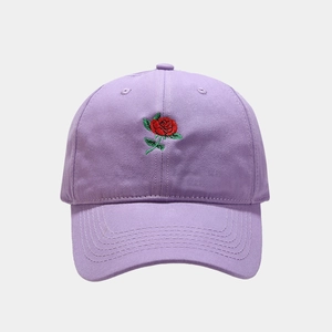 Close-up of red rose embroidery on purple cotton baseball cap with detailed stitching