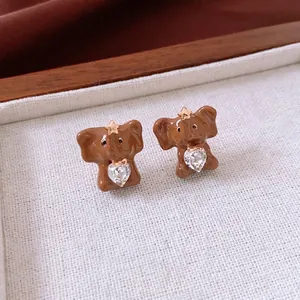 Vintage elephant stud earrings with heart-shaped zircon on a textured background