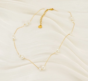 Detail of 18K gold stainless steel chain with assorted white pearls on silk fabric