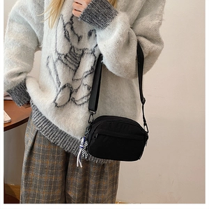 Détail d'un sac bandoulière minimaliste en nylon noir avec une sangle réglable en tissu