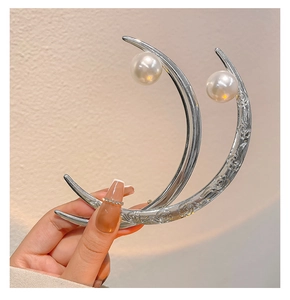 Close-up of silver crescent hair pin featuring rose carvings and white pearls