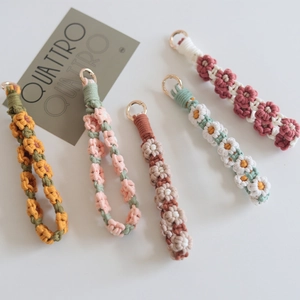 Detailed view of woven daisy keychains in various colors with golden metal rings