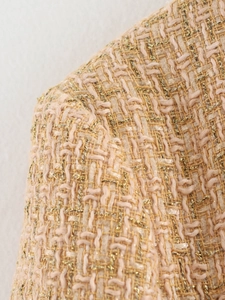 Detailed macro texture of light apricot tweed fabric with golden metallic silk thread