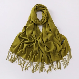 Detailed close-up of green cashmere scarf showing fringe texture and premium fabric label